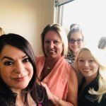 A group of women are posing for a selfie in front of a window.