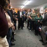 A group of people are standing in a room talking to each other.