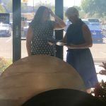Two women are standing next to each other in front of a window in a restaurant.