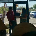 A man and a woman are standing in front of a window in a restaurant.