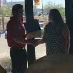 A man and a woman are shaking hands in front of a window.