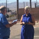 A man and a woman are standing next to each other on the side of the road . the woman is wearing a blue dress.