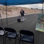 A man is standing in the middle of a road under a blue tent.