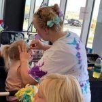 A woman is brushing a child 's hair in a salon.