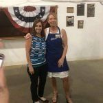 Two women are posing for a picture in front of an american flag.