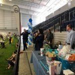 A group of people are standing around tables in an indoor stadium.