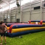 A group of people are standing next to a large inflatable in a building.