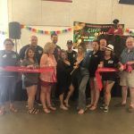 A group of people are standing in a room holding red ribbons.