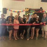 A group of people are standing next to each other holding a red ribbon.