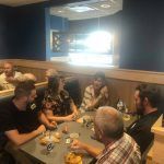 A group of people are sitting around a table in a restaurant.