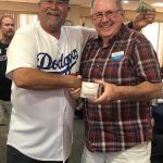 Two men are posing for a picture together and one of them is wearing a dodgers jersey.