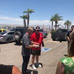 A group of people are standing in a parking lot talking to each other.