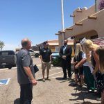 A group of people are standing in a parking lot in front of a building.