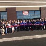A group of people are standing in front of a building holding ribbons.
