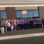 A group of people are standing in front of a building holding ribbons.