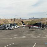 A helicopter is parked in a parking lot next to a trailer.