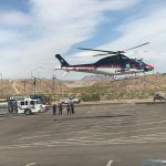 A helicopter is flying over a parking lot.