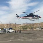 A helicopter is flying over a parking lot.