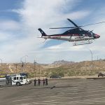 A helicopter is flying over a parking lot.