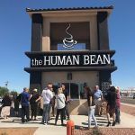 A group of people are standing outside of the human bean coffee shop.