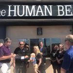 A group of people are standing in front of a building with a sign that says `` the human being ''.