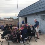 A group of people are sitting around a table outside of a building.