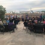 A group of people are sitting at tables and chairs on a patio.