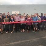 A group of people are standing next to each other holding a red ribbon.