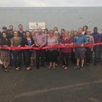 A group of people are standing next to each other holding red ribbons.