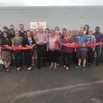 A group of people are standing next to each other holding red ribbons.