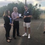 A group of people are standing in a parking lot talking to each other.