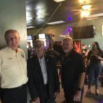 Three men are standing next to each other in a room.