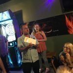 A man is giving a speech in front of a group of people in a restaurant.