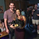 A man and a woman are standing next to each other in a room holding a trophy.