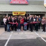 A group of people are standing in front of a smoke shop.