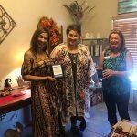 Three women are standing next to each other in a room holding a plaque.