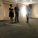 A group of people are standing in a room talking to each other.