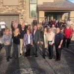 A group of people are posing for a picture in front of a house.