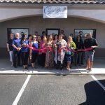 A group of people are standing in front of a building holding ribbons.