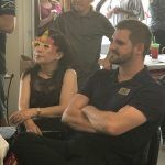 A man and a woman are sitting in a chair with their arms crossed.