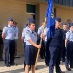 A group of soldiers are standing in front of a building holding a flag.