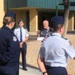 A group of soldiers are standing on a sidewalk in front of a building.