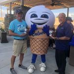 Two men are standing next to an ice cream cone mascot.