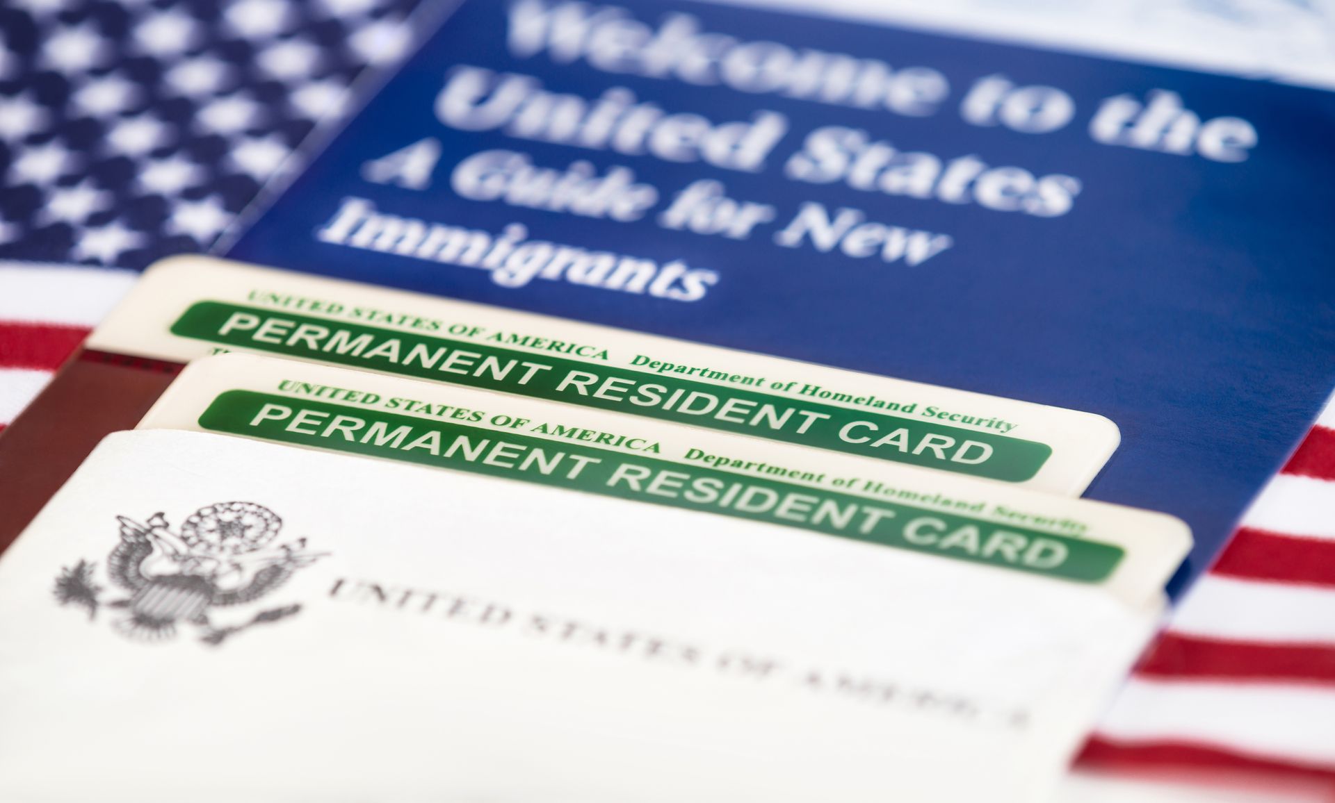 A united states permanent resident card is sitting on top of an american flag.