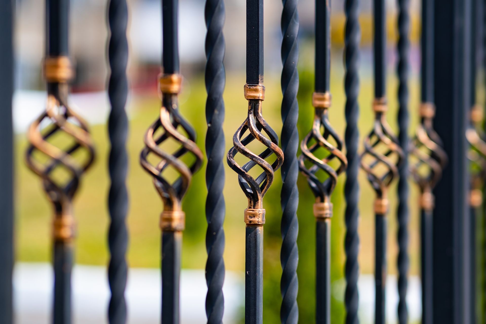 Ornamental iron fence with twisted black bars and gold diamond accents outdoors.