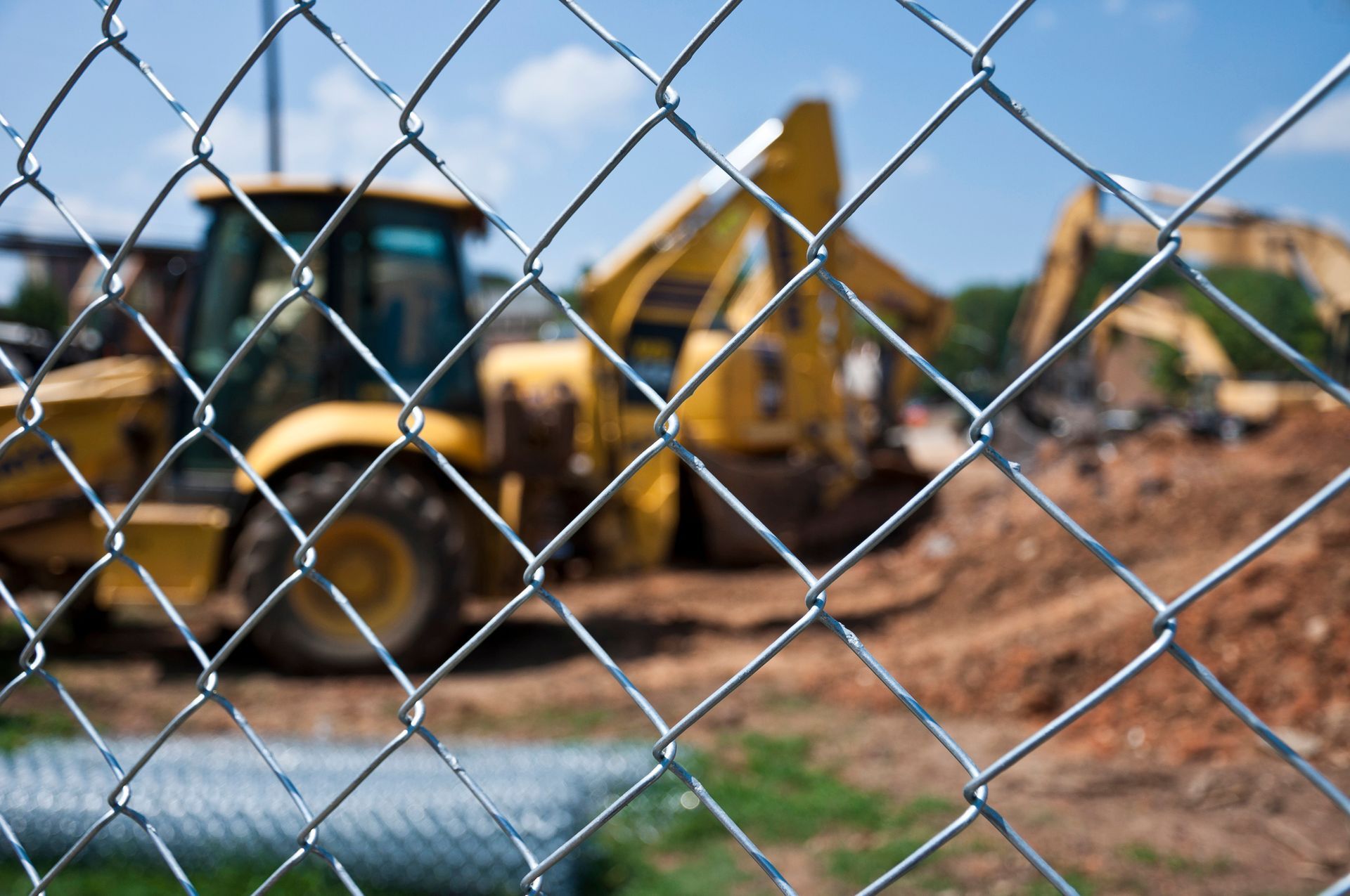 Excavator at work on dusty construction site behind fence. Excavator at work on dusty construction site behind fence.