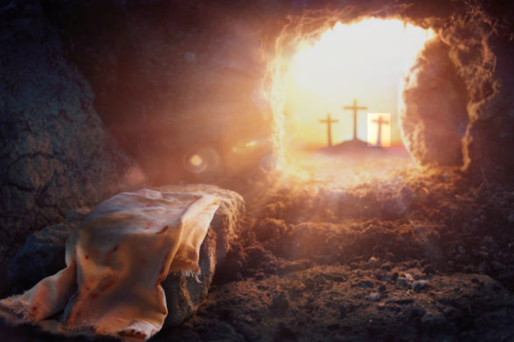 Empty tomb with sunlight streaming through; three crosses in the distance.