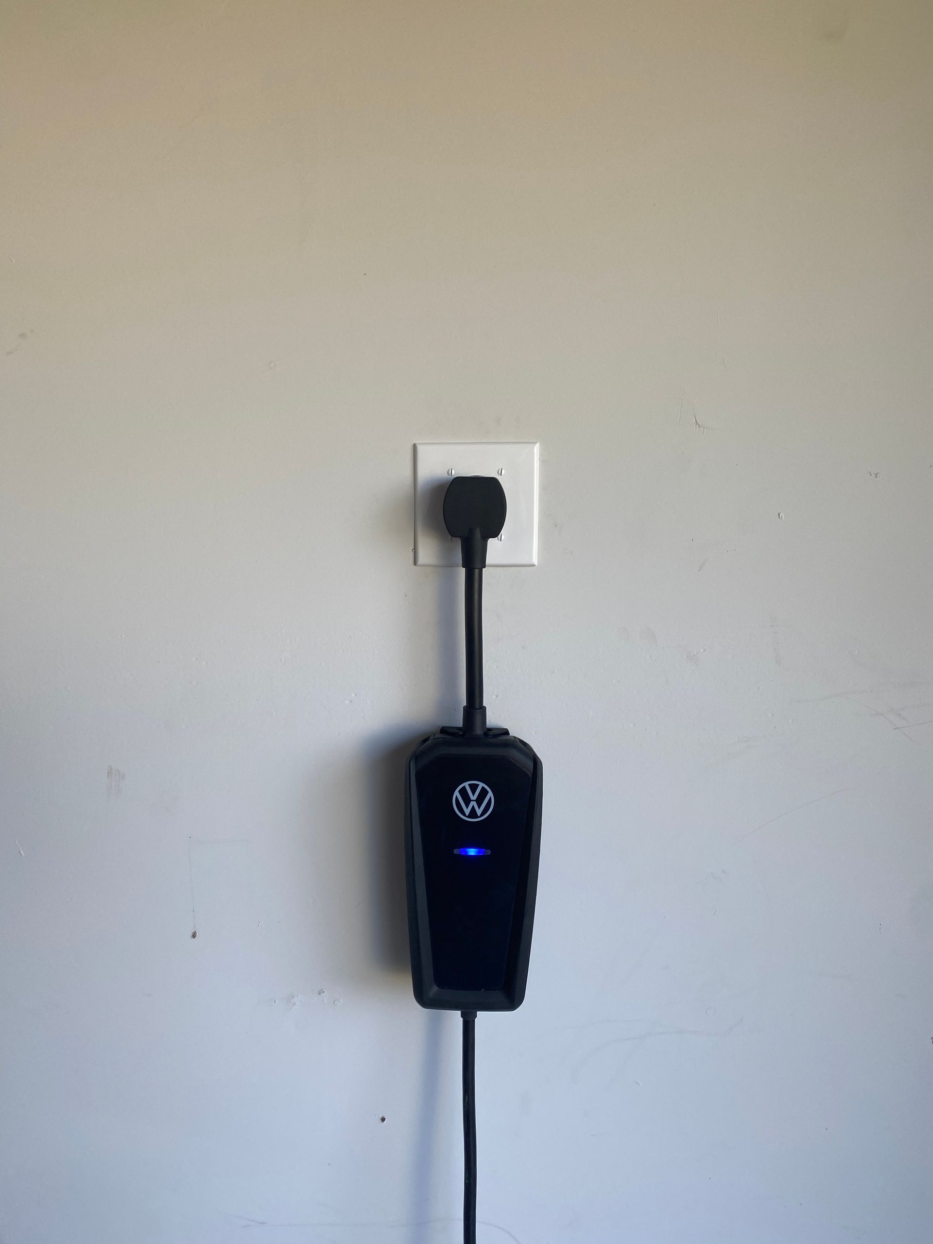 A volkswagen electric car charger is plugged into a wall outlet.