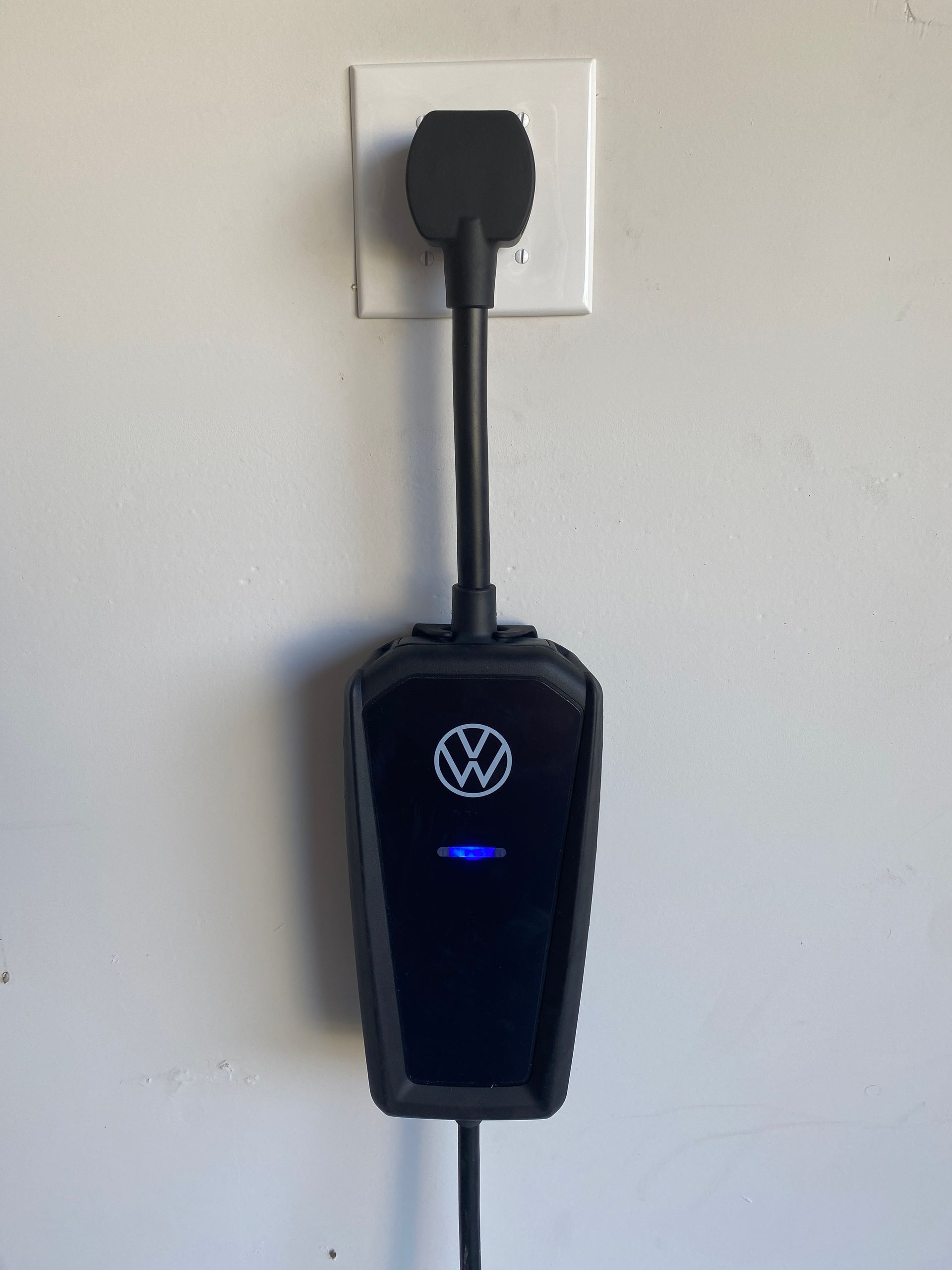 A volkswagen charging station is plugged into a wall outlet.