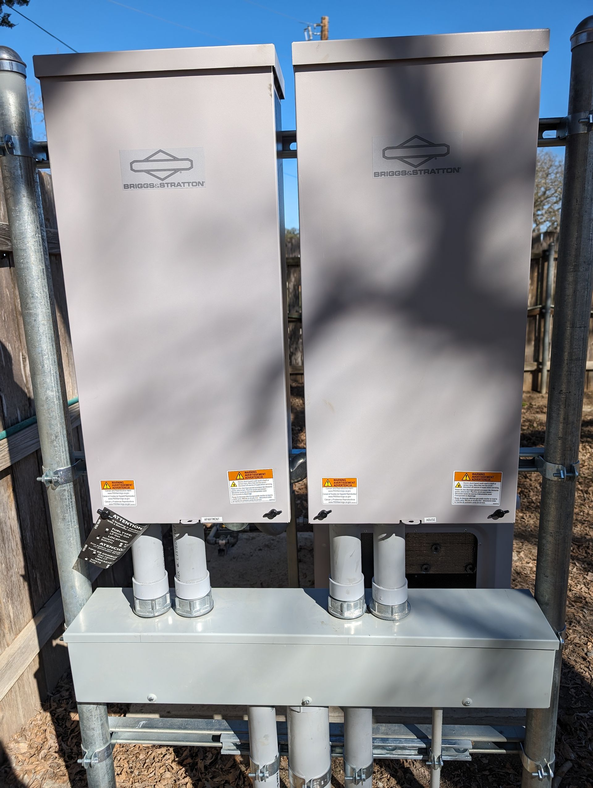 Two electrical boxes are sitting next to each other on a fence.